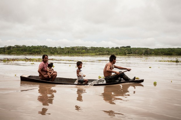 Macedonia, Colombia, Mar 05, 2009: A Ticuna family in their canoe in the Amazon River. They come from Macedonia a small riparian village in the Colombian part of the Amazon River. Native people are gradually losing their identity over the years, through alcoholism, drug abuse, and violence. People try to make a living working in the few jobs that are available in the village apart from tourism.